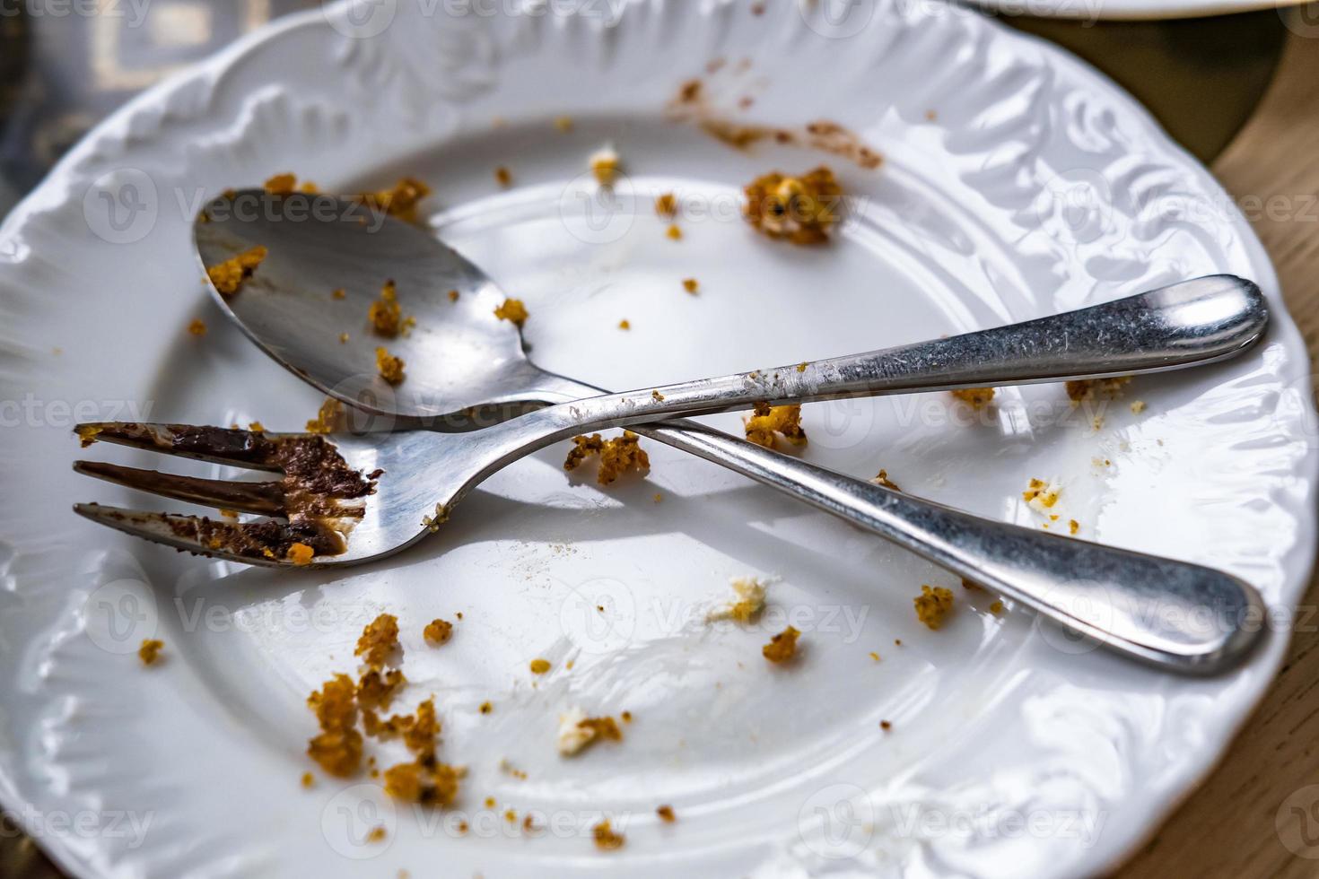 leeg vuil bord met lepel en vork Aan de tafel na ontbijt foto