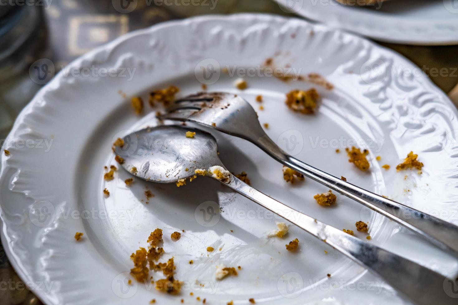 leeg vuil bord met lepel en vork Aan de tafel na ontbijt foto