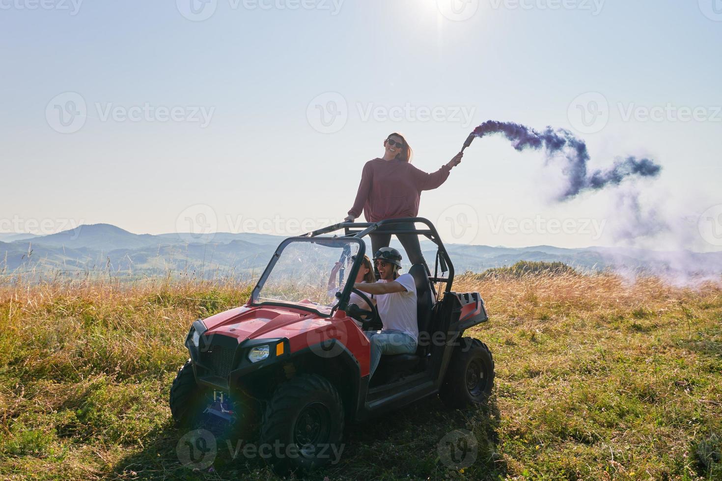 opgewonden mensen hebben pret genieten van mooi zonnig dag Holding kleurrijk fakkels terwijl het rijden een uit weg buggy auto foto