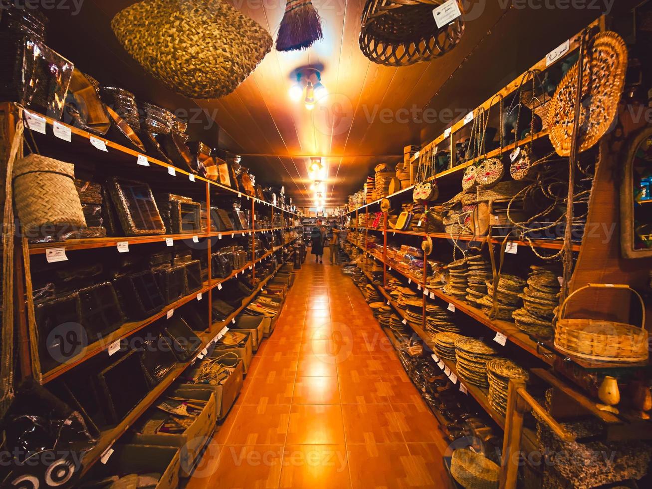 bandar anzali, iran, 2022 - toerist vrouw onderzoeken handgemaakt producten manden accessoires winkel in bandar anzali foto