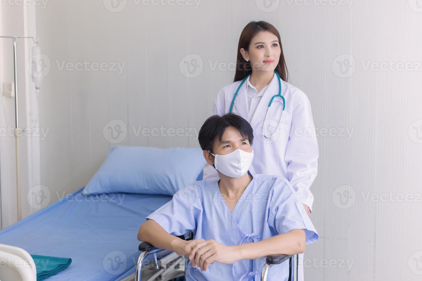 aziatische doktersvrouw die praat met een man-patiënt die een gezichtsmasker draagt over zijn gezondheidssymptoom terwijl hij in een rolstoel in het ziekenhuis zit. foto