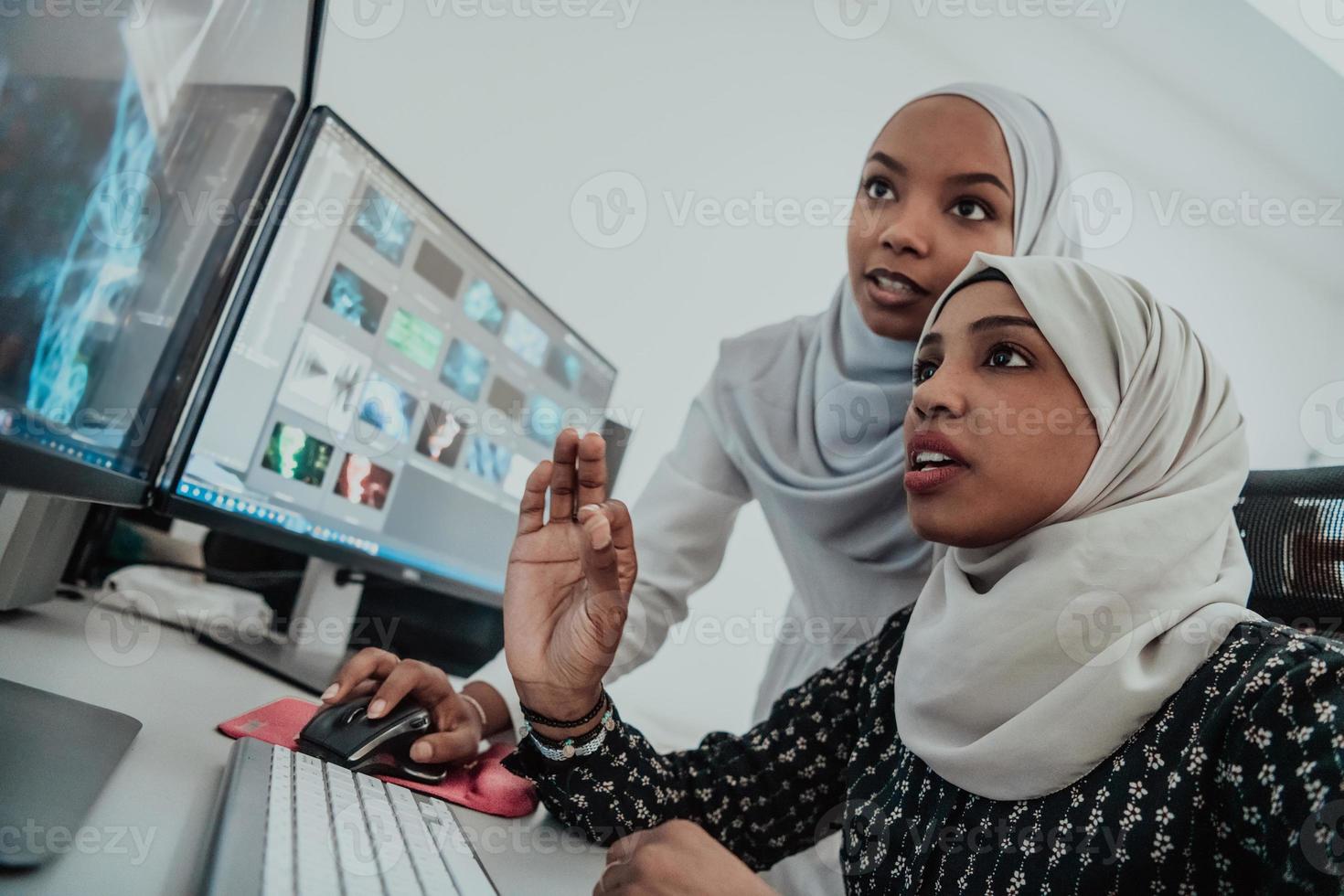 vrienden Bij de kantoor twee jong afro Amerikaans modern moslim onderneemsters vervelend sjaal in creatief helder kantoor werkplaats met een groot scherm foto