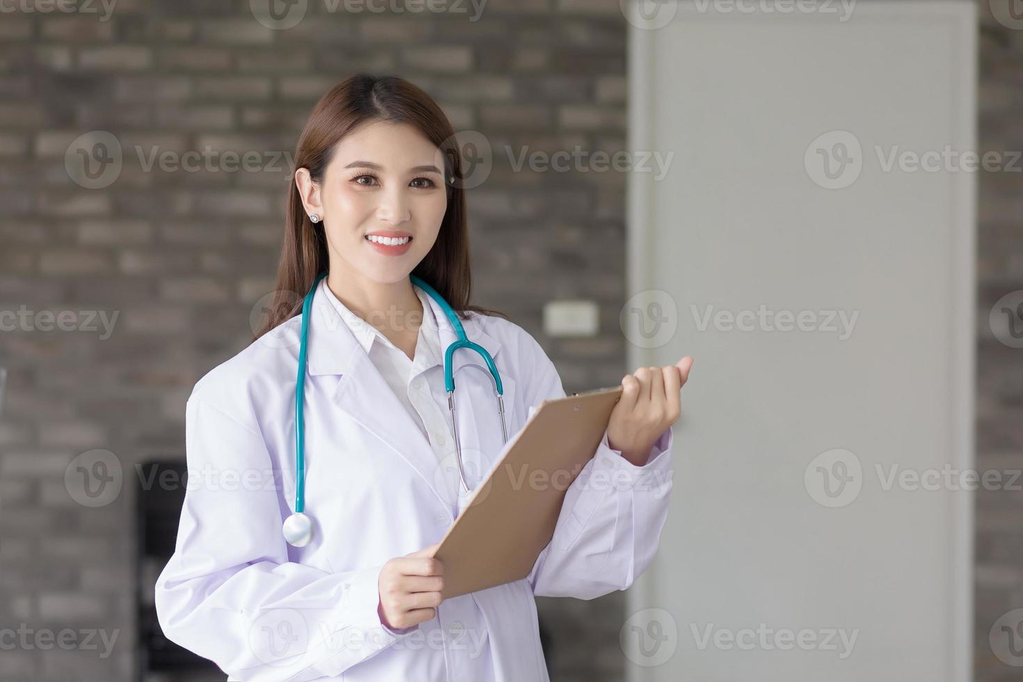 Aziatisch vrouw dokter met een wit laboratorium jas staan en houden een klembord in haar hand- Bij werk kantoor in ziekenhuis. coronavirus bescherming concept. foto