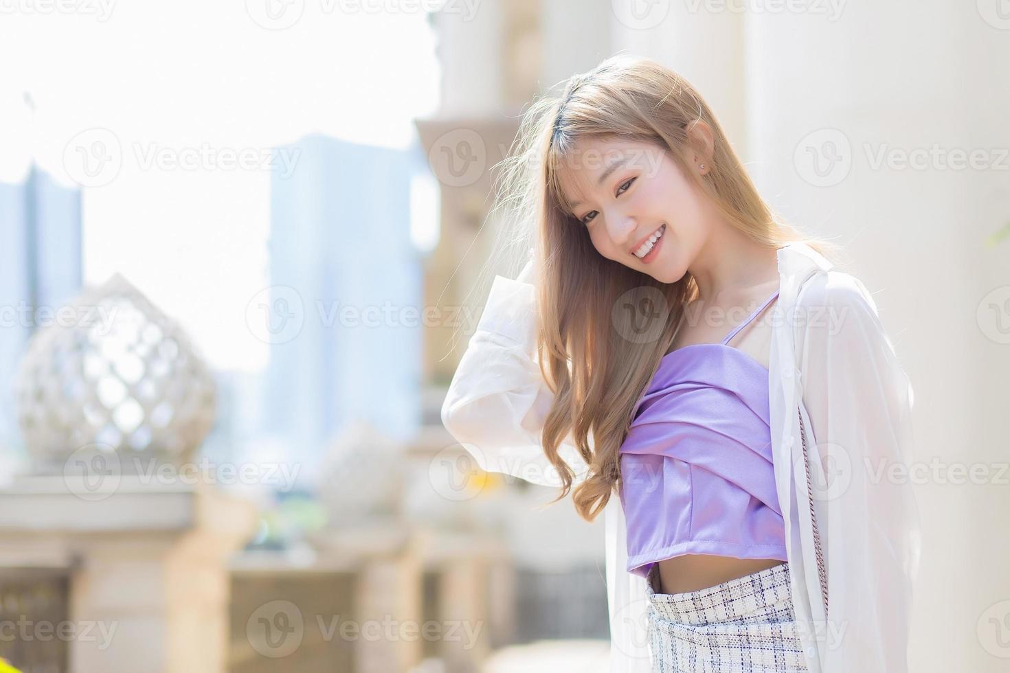 Aziatisch mooi dame wie heeft bronzen haar- glimlacht en wandelingen Aan de straat in mode stijl thema. foto