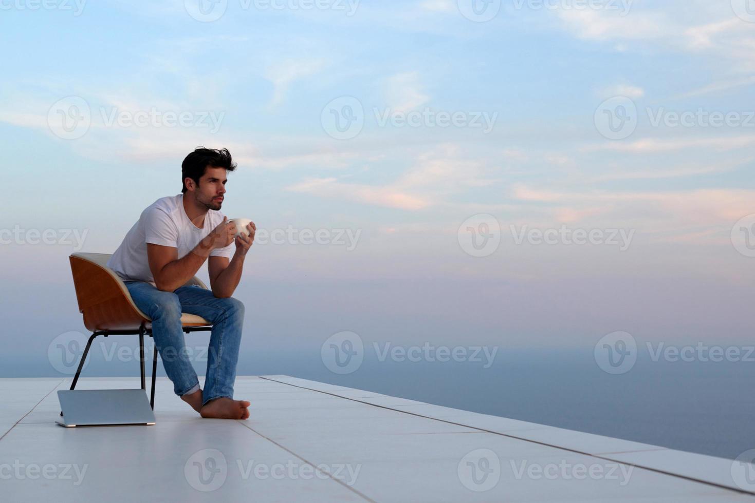 ontspannen jong Mens Bij huis Aan balkon foto