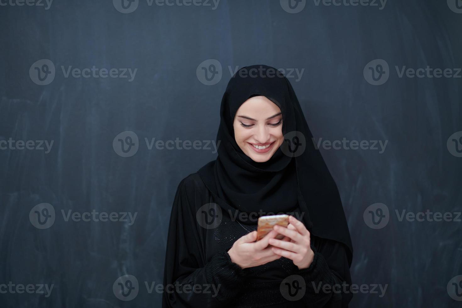 jong moslim zakenvrouw in traditioneel kleren of abaya gebruik makend van smartphone foto