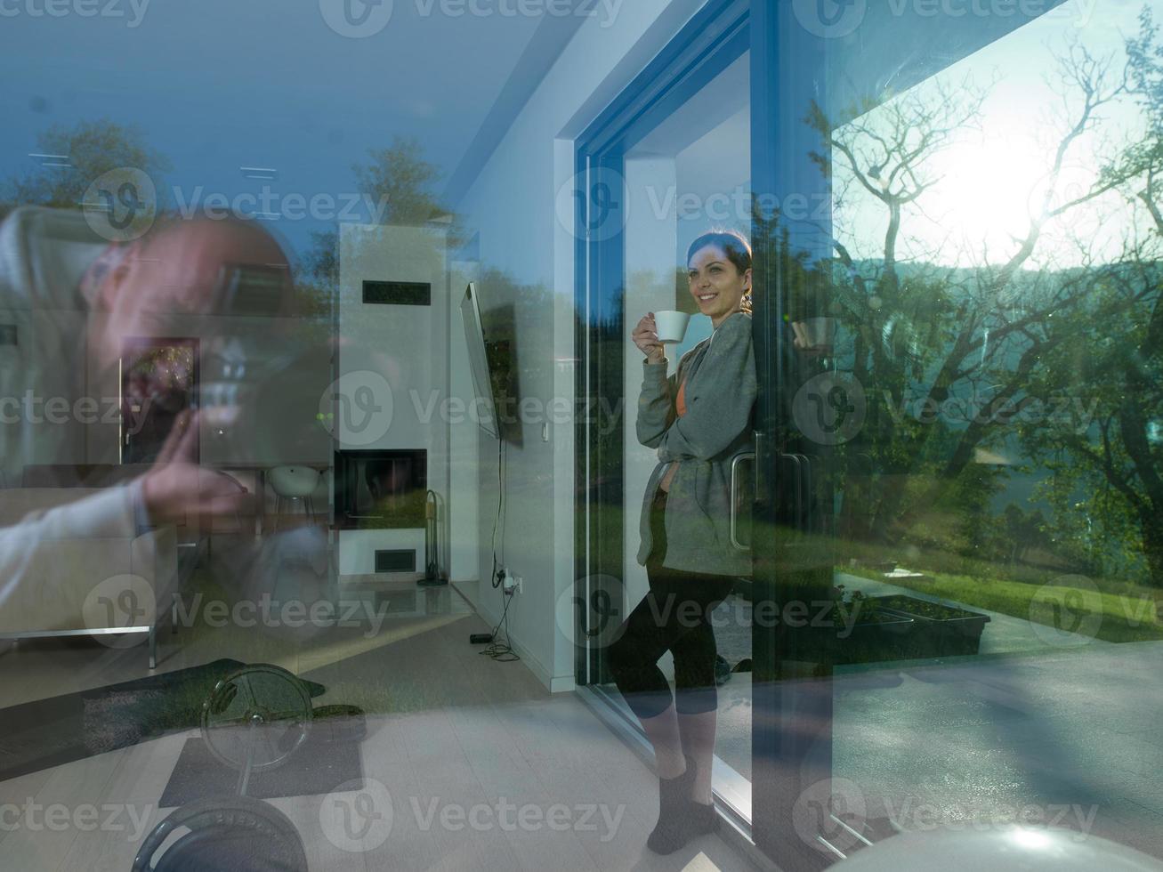 vrouw drinken koffie in voorkant van haar luxe huis villa foto