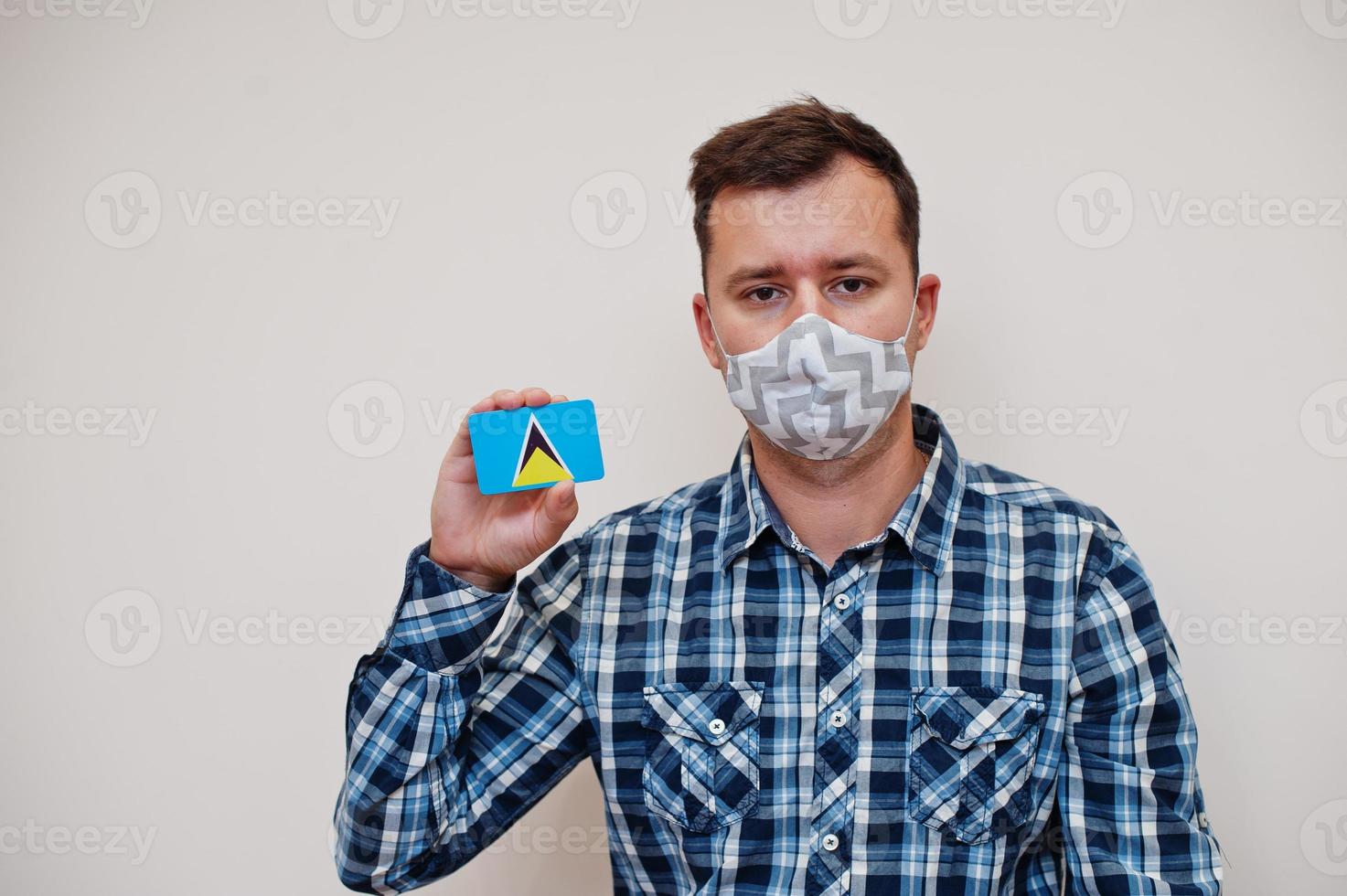 Mens in geruit overhemd tonen heilige lucia vlag kaart in hand, slijtage beschermen masker geïsoleerd Aan wit achtergrond. Amerikaans landen coronavirus concept. foto