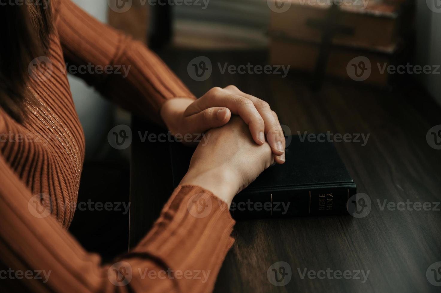 handen samen in gebed naar god langs met de Bijbel in de christen concept en geloof, vrouw bidden in de Bijbel Aan de tafel foto