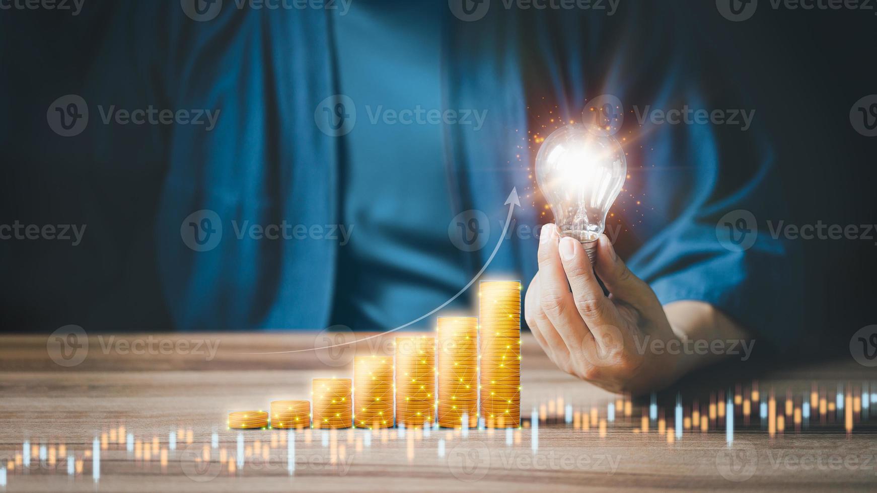 hand- Holding een licht lamp en een stapel van munten. creativiteit in besparing geld, investeren, geld beheer voor de toekomst. foto