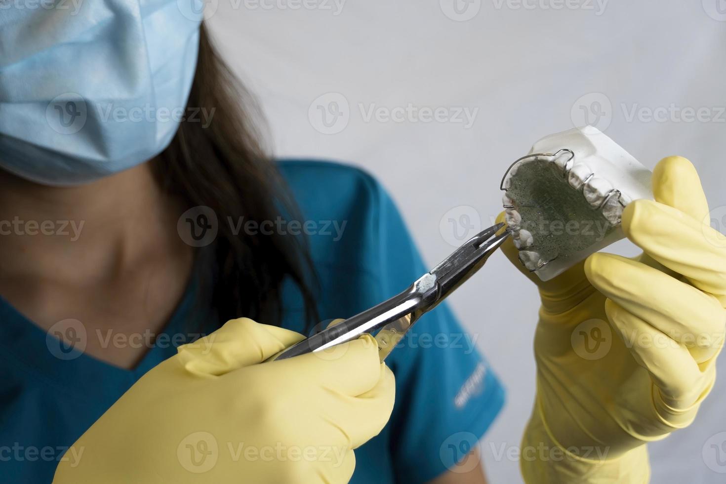 de vrouw tandarts is Holding kunstgebit in zijn handen en instrumenten foto
