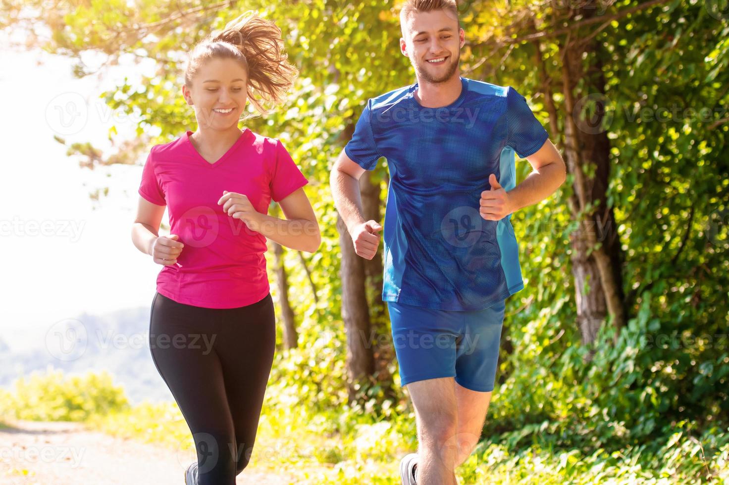 jong paar jogging Aan zonnig dag Bij natuur foto