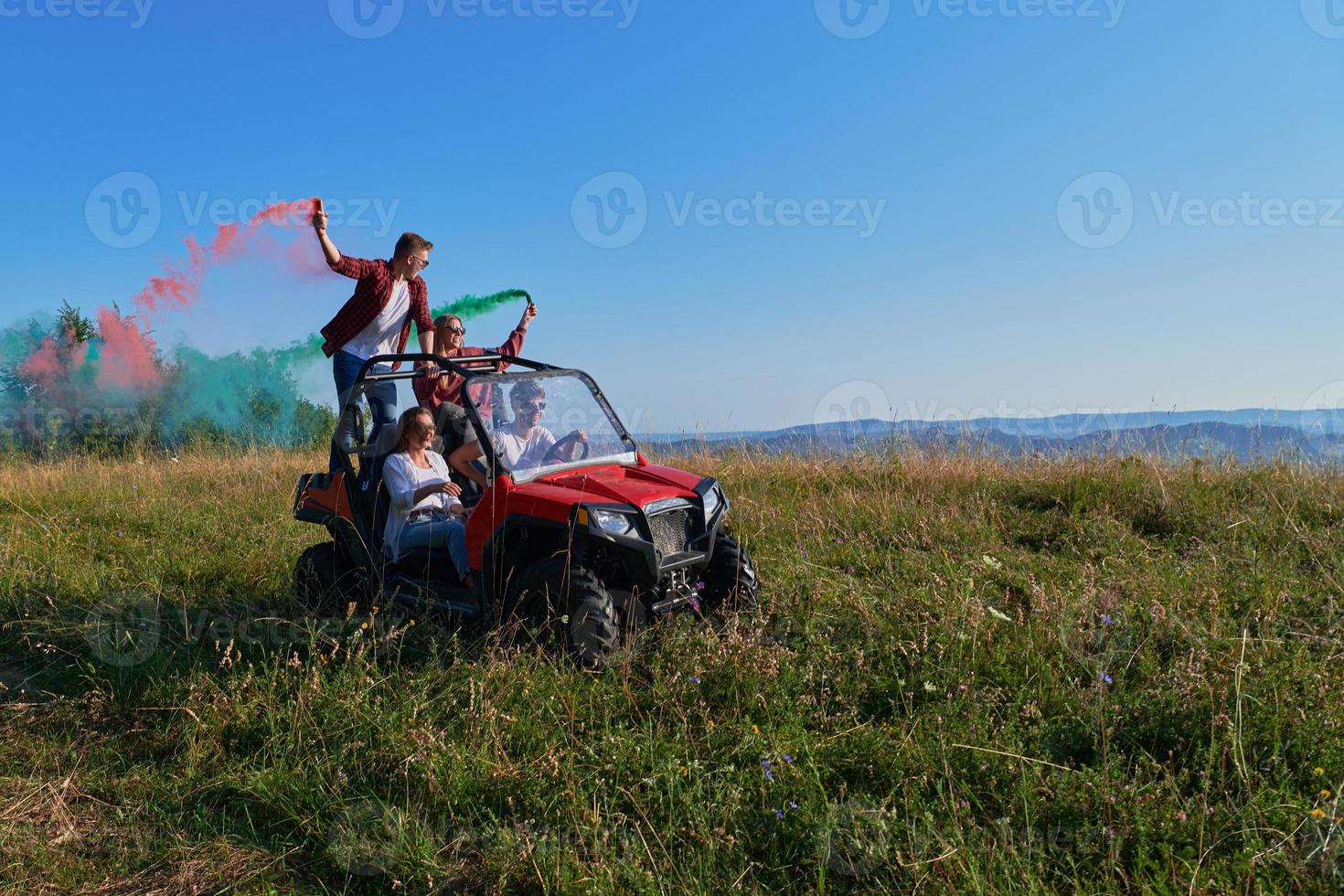 opgewonden mensen hebben pret genieten van mooi zonnig dag Holding kleurrijk fakkels terwijl het rijden een uit weg buggy auto foto