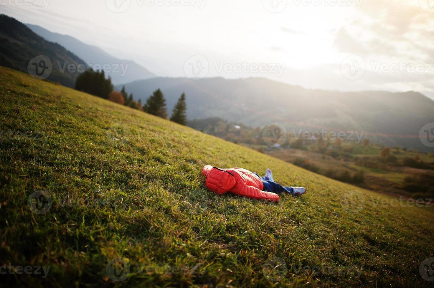 jongen liggend in het gras met een prachtige bergketen aan de horizon. foto