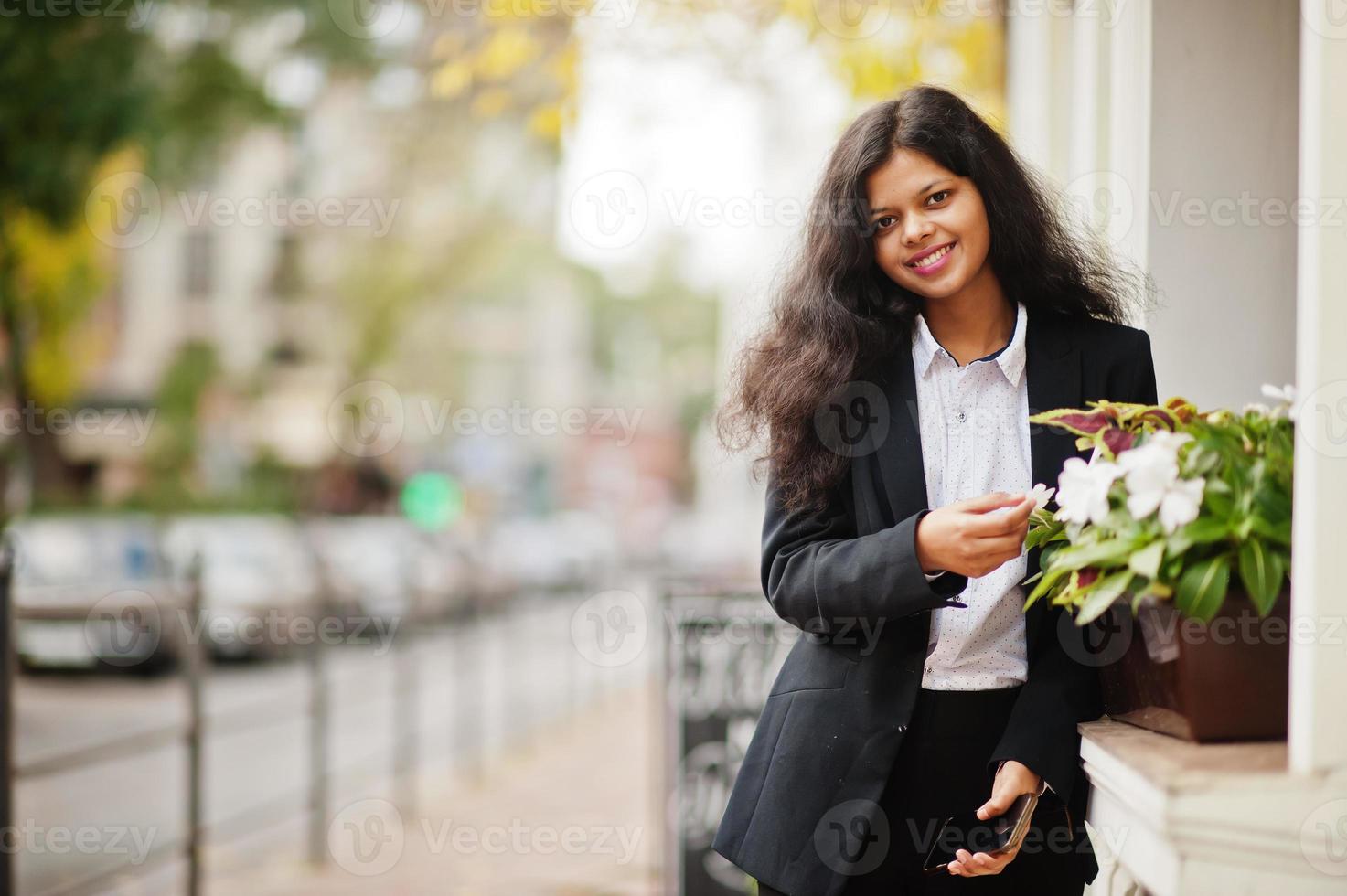 prachtig Indisch vrouw slijtage formeel poseren Bij straat met mobiel telefoon Bij handen. foto