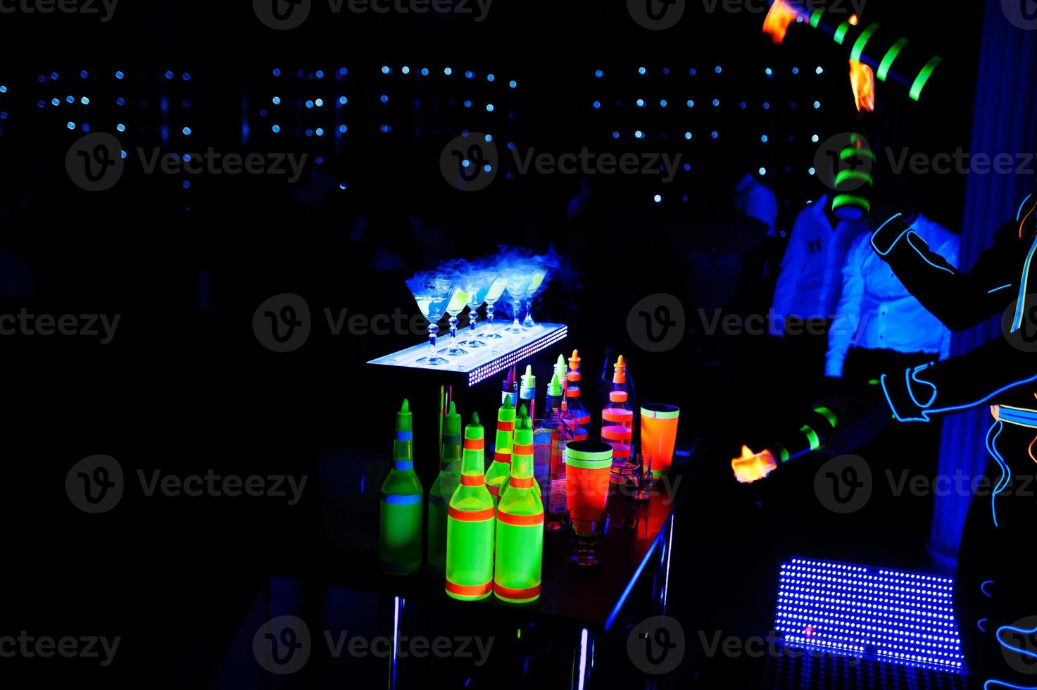 professioneel barman en LED licht brand show. silhouet van modern barman beven drinken Bij nacht cocktail bar. foto