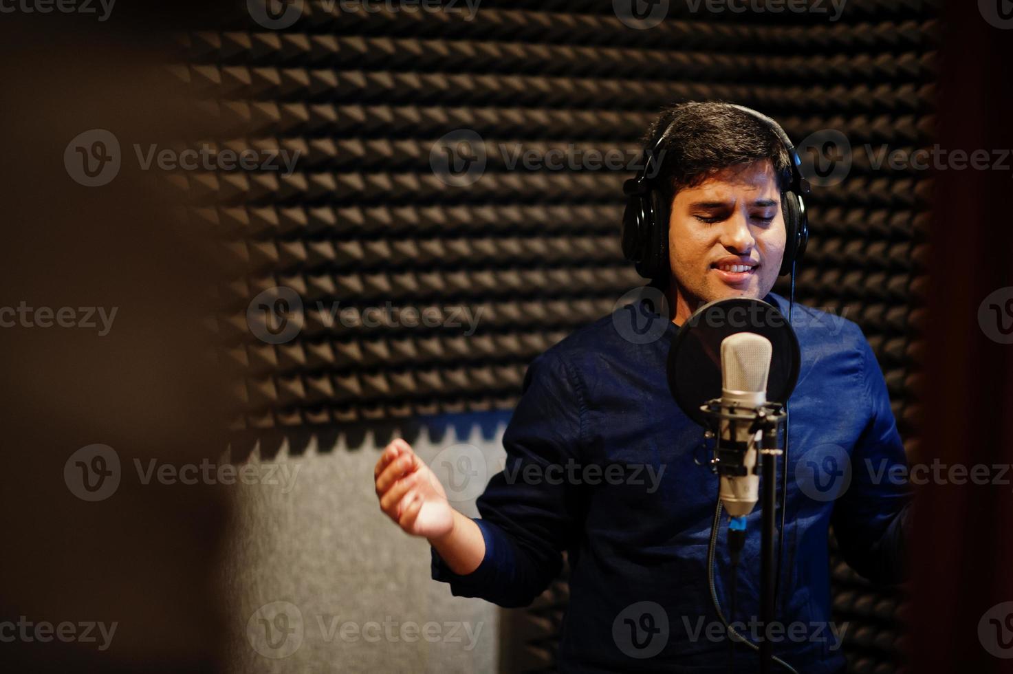 jong Aziatisch zanger Mens met microfoon opname lied in Vermelding muziek- studio. foto