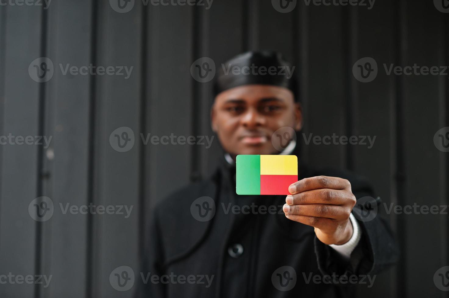 Afrikaanse Mens slijtage zwart durag houden Benin vlag Bij hand- geïsoleerd donker achtergrond. foto