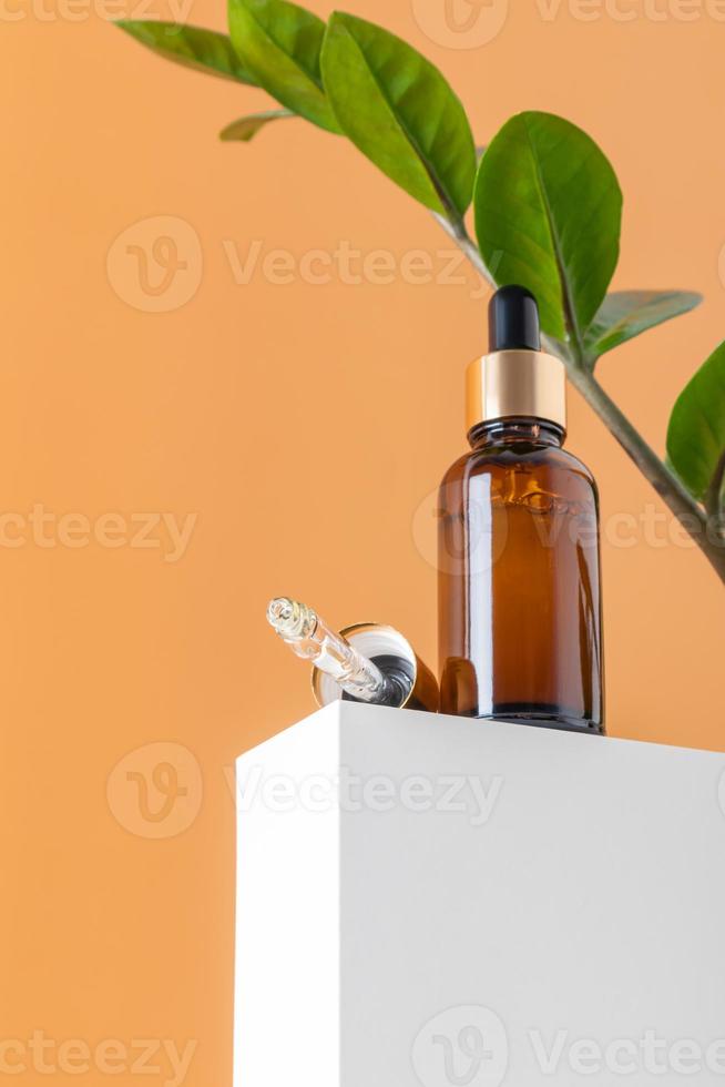 glas kunstmatig flessen met olie of serum voor huid zorg Aan speciaal podium Aan beige achtergrond. natuurlijk huid zorg concept. foto