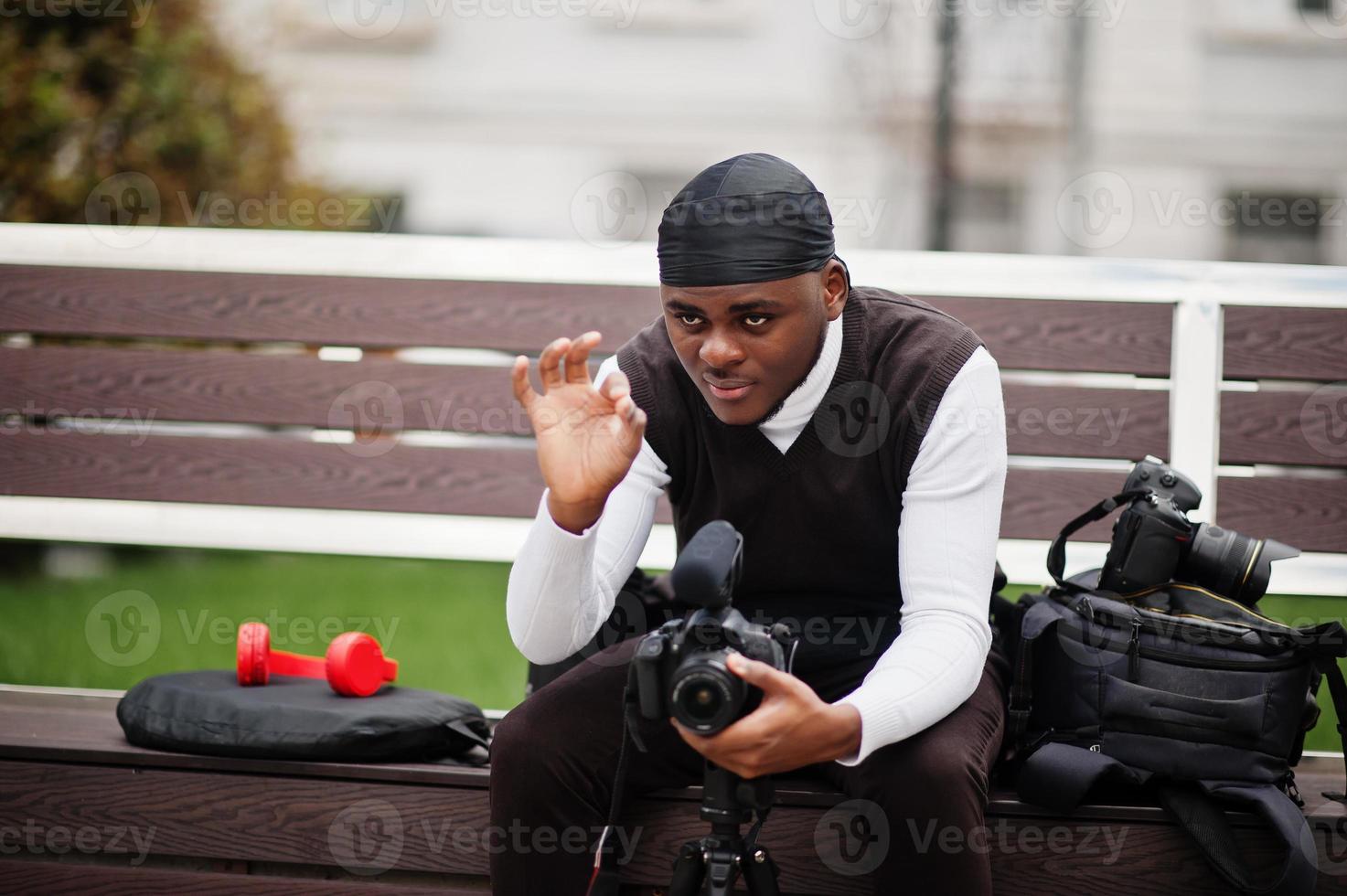 jong professioneel Afrikaanse Amerikaans videograaf Holding professioneel camera met pro apparatuur. afro cameraman vervelend zwart Duraq maken een videos. foto