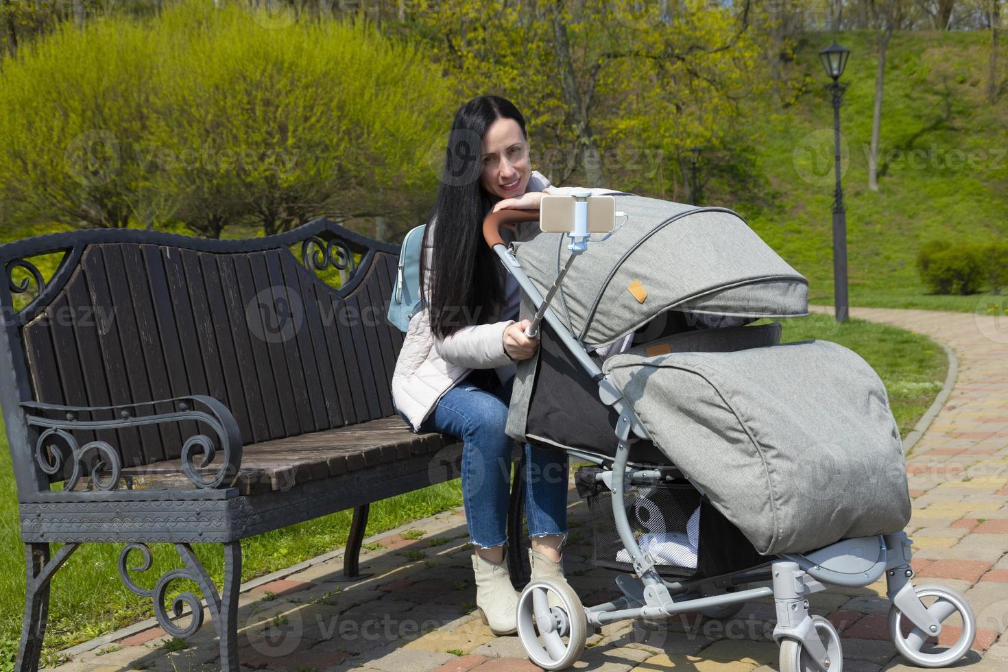 Momentum Doe herleven Sprong jong mooi moeder in donker haar, een vrouw met een schattig baby in een  kinderwagen maakt een selfie van de telefoon. 11023882 Stockfoto