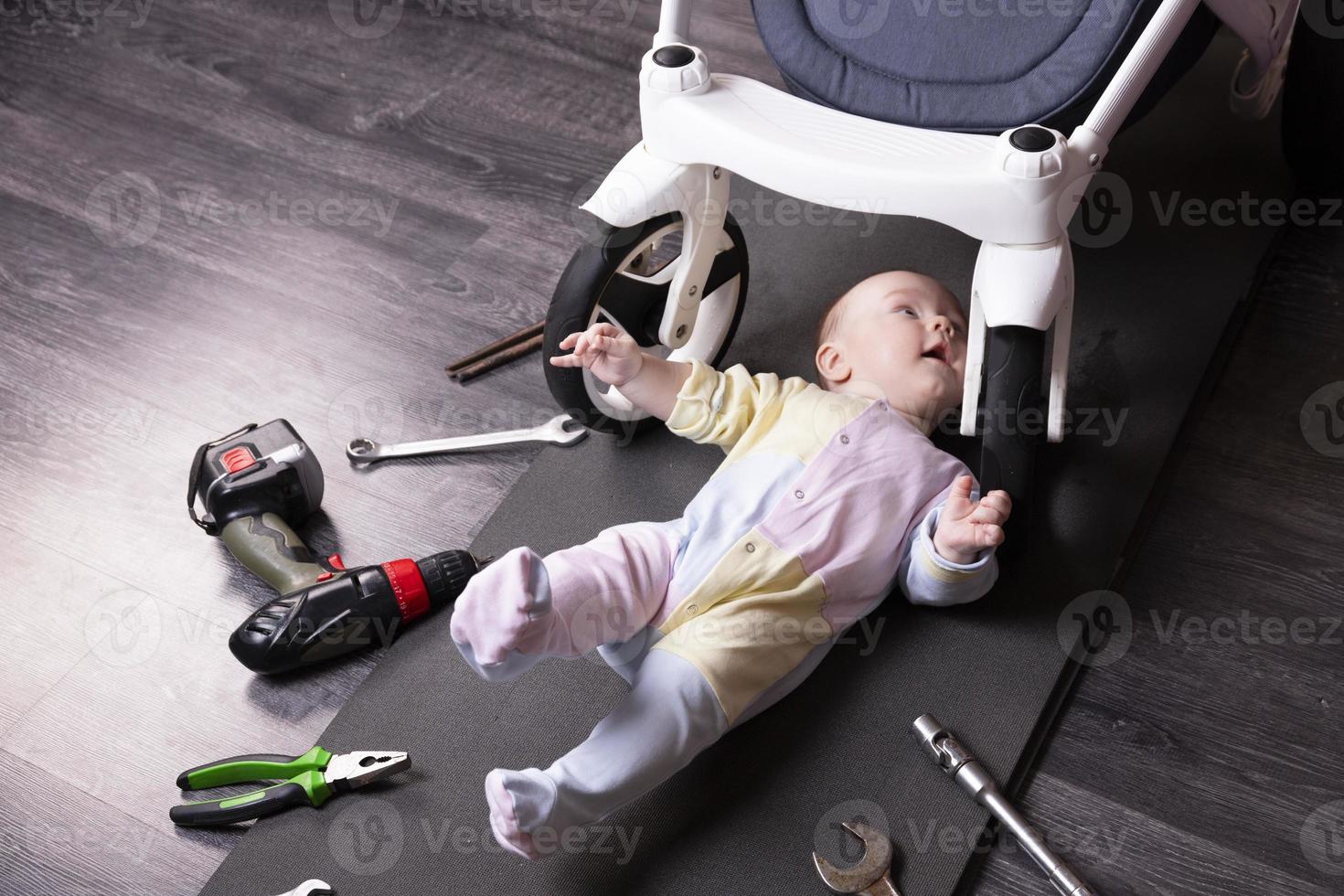 jongen monteur reparaties de suspensie van een baby koets. wij reparatie alles dat reizen. humor, uitdaging. foto