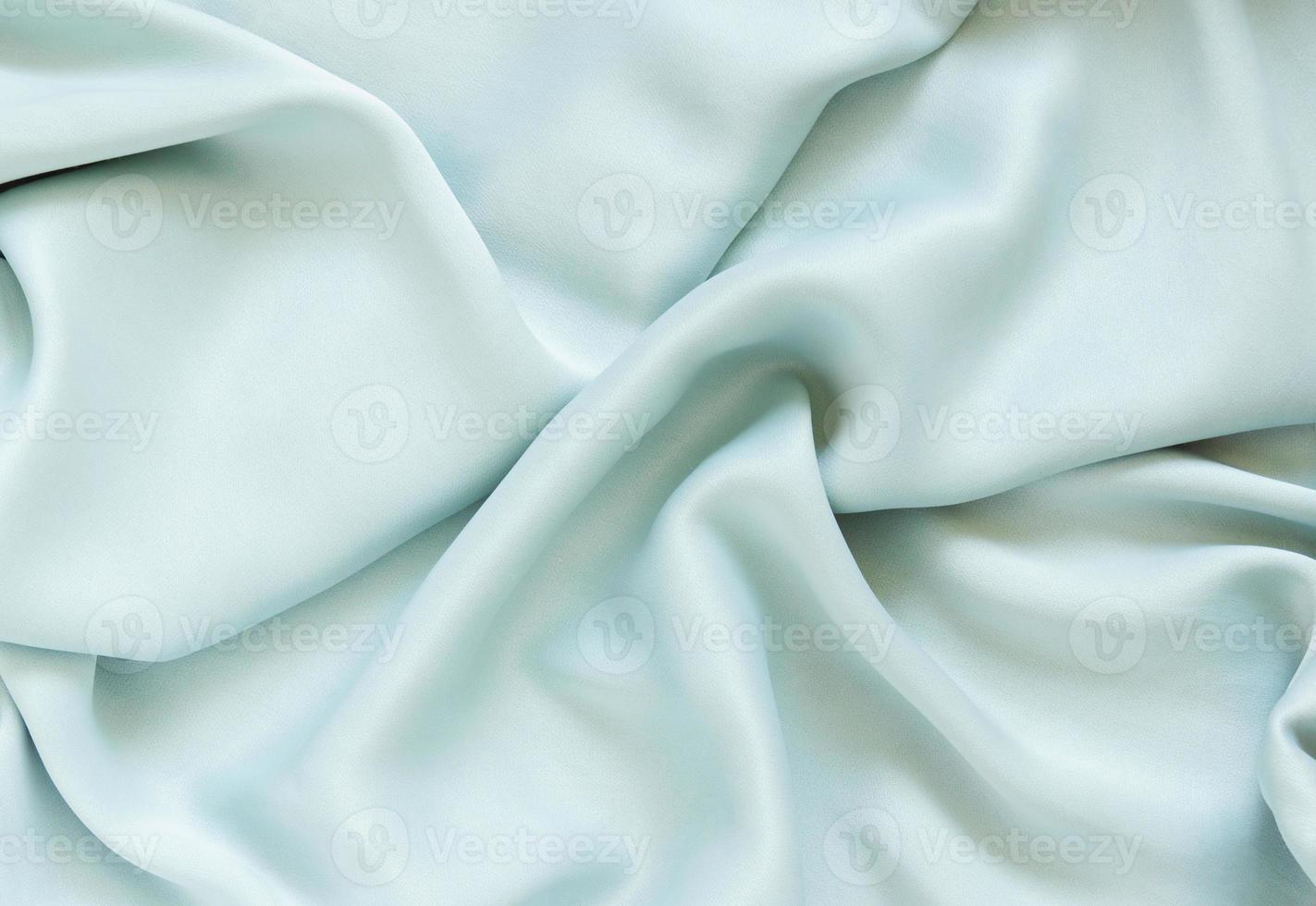 zijde gedrapeerd munt kleding stof met plooien en schitteren. getextureerde achtergrond van delicaat groen kleur. foto