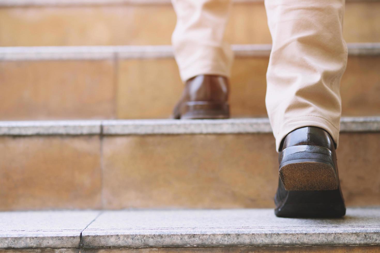 close-up benen schoenen van jonge zakenman een persoon lopen intensivering de trap opgaan in de moderne stad, omhoog gaan, succes, opgroeien. met filtertonen retro vintage warm effect. trap foto