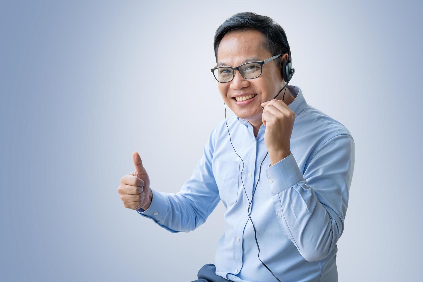 mens die op middelbare leeftijd vraag op hoofdtelefoon neemt die op blauwe achtergrond wordt geïsoleerd foto