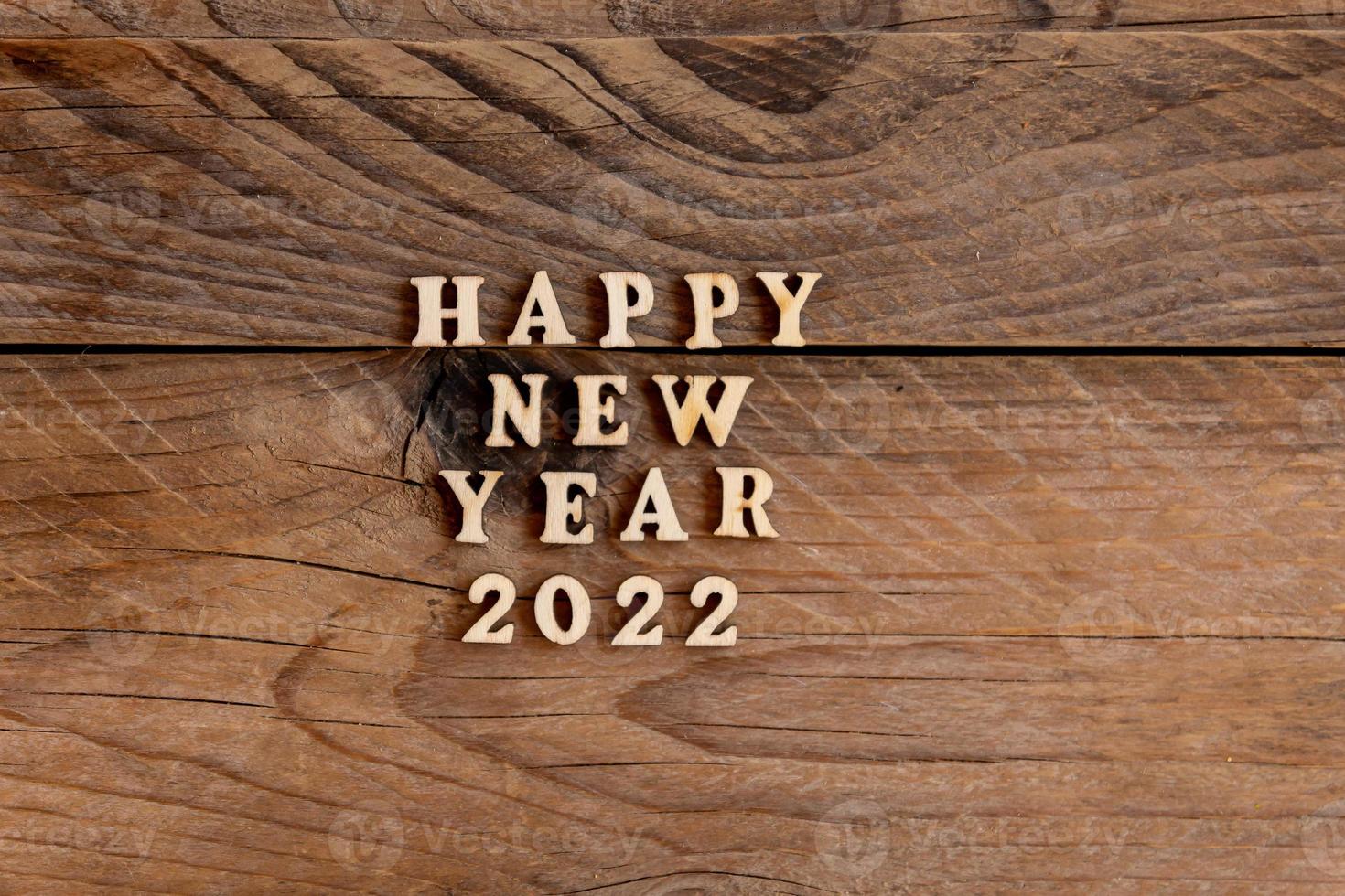 gelukkig nieuw jaar 2022. citaat gemaakt van houten brieven en getallen 2022 Aan houten achtergrond. creatief concept voor nieuw jaar groet kaart foto
