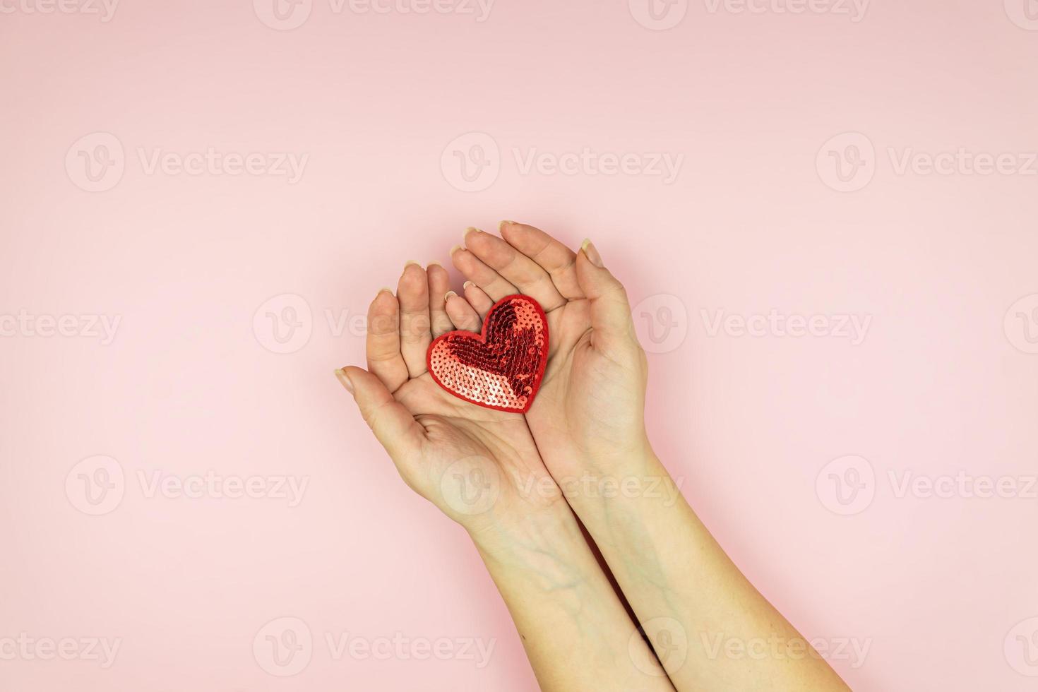 vrouw handen Holding rood pailletten hart Aan roze achtergrond. creatief minimaal lay-out met kopiëren ruimte foto