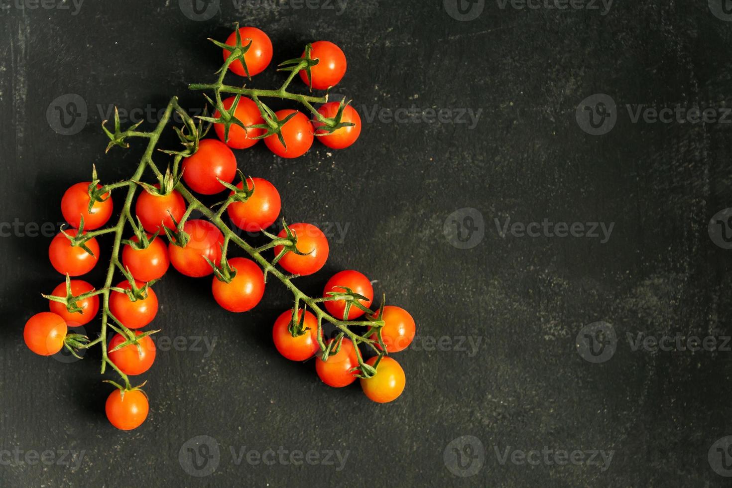 top visie van vers rijp kers tomaten Aan zwart achtergrond met kopiëren ruimte. ingrediënt voor middellandse Zee keuken. foto