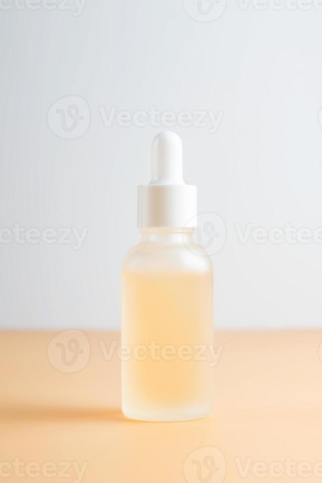 kant visie van berijpt glas druppelaar fles met schoonheid gezicht olie Aan beige achtergrond. anti veroudering serum met natuurlijk ingrediënten. foto