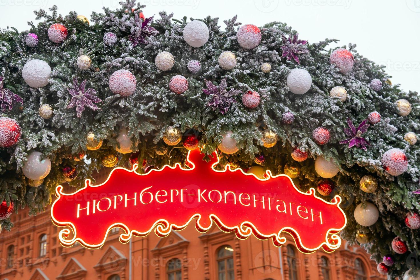 Kerstmis boog versierd met kerstballen en sneeuw. rood uithangbord met woord in Russisch Neurenberg - Kopenhagen . Moskou seizoenen project foto