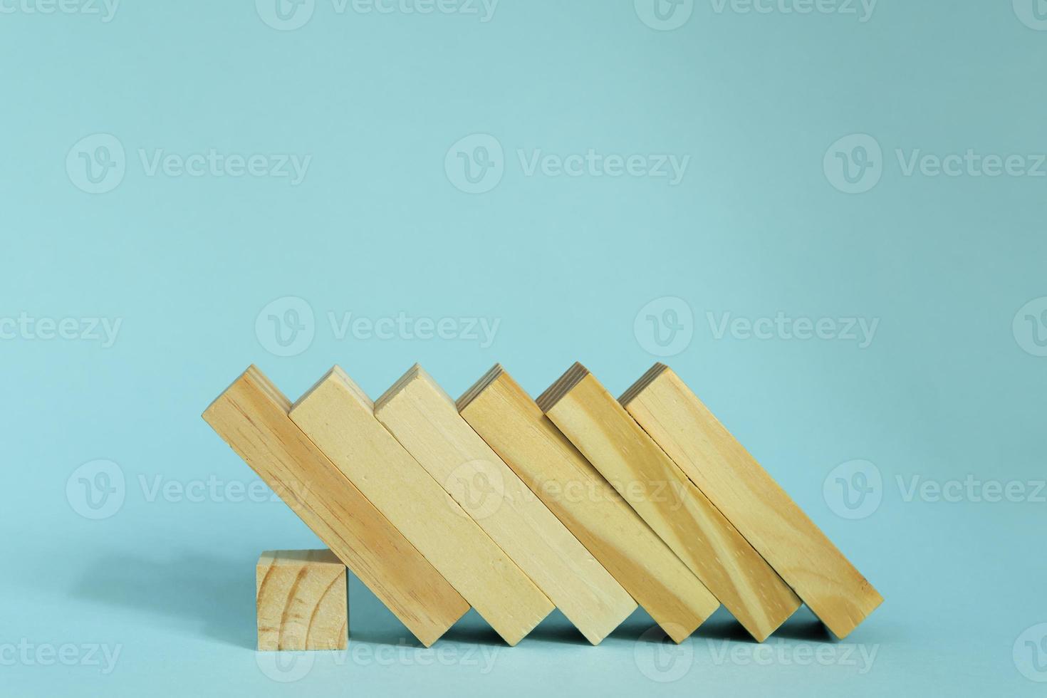 houten blokken Aan blauw achtergrond. domino effect in bedrijf concept. foto