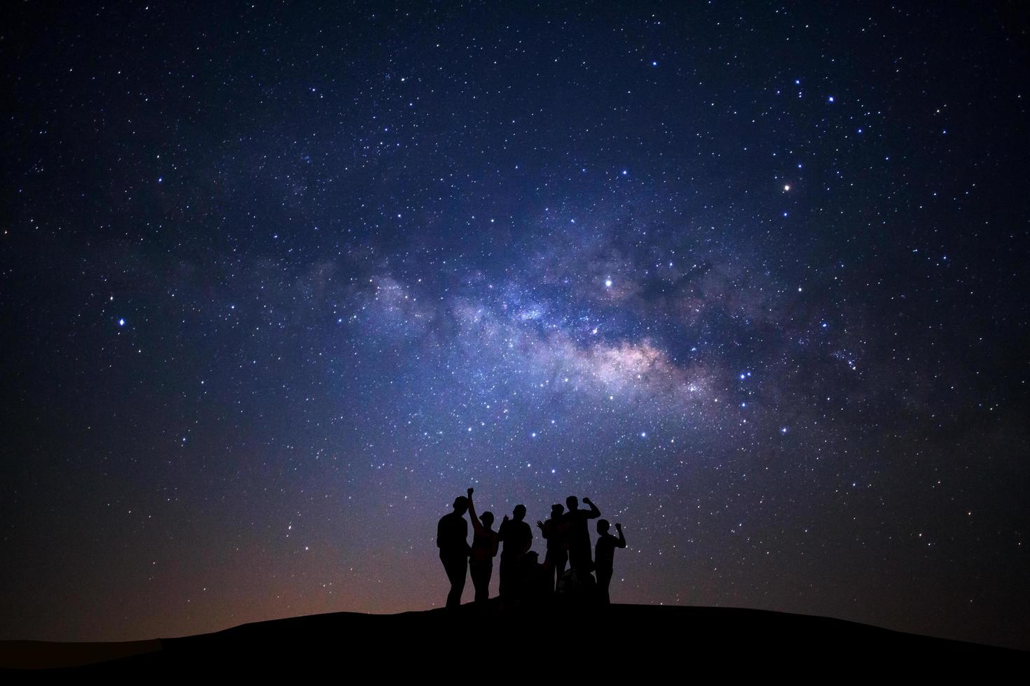 landschap met melkachtig manier, nacht lucht met sterren en silhouet van gelukkig Mens staand Aan hoog moutain foto