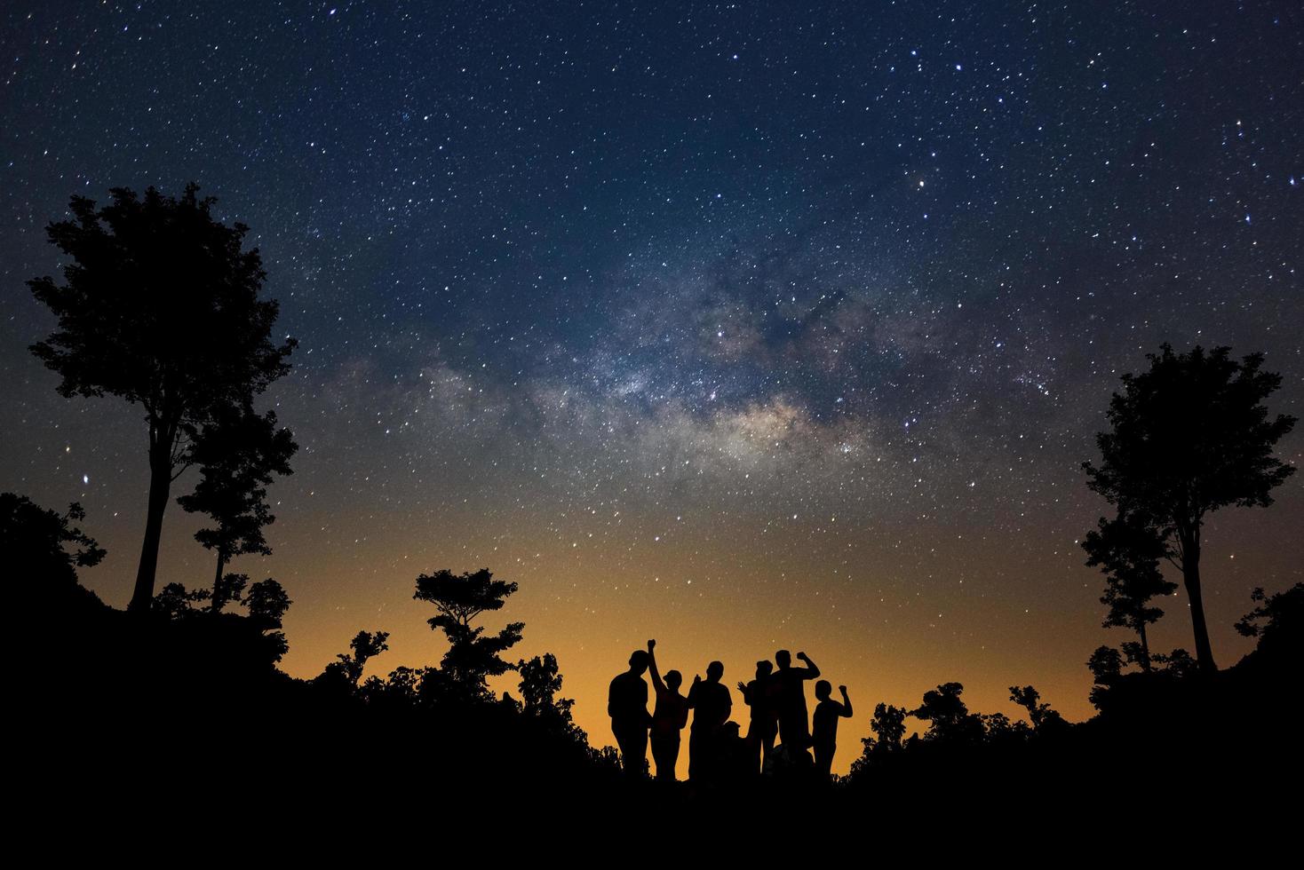 landschap met melkachtig manier, nacht lucht met sterren en silhouet van gelukkig mensen staand in Woud, lang blootstelling fotograaf, met korrel. foto