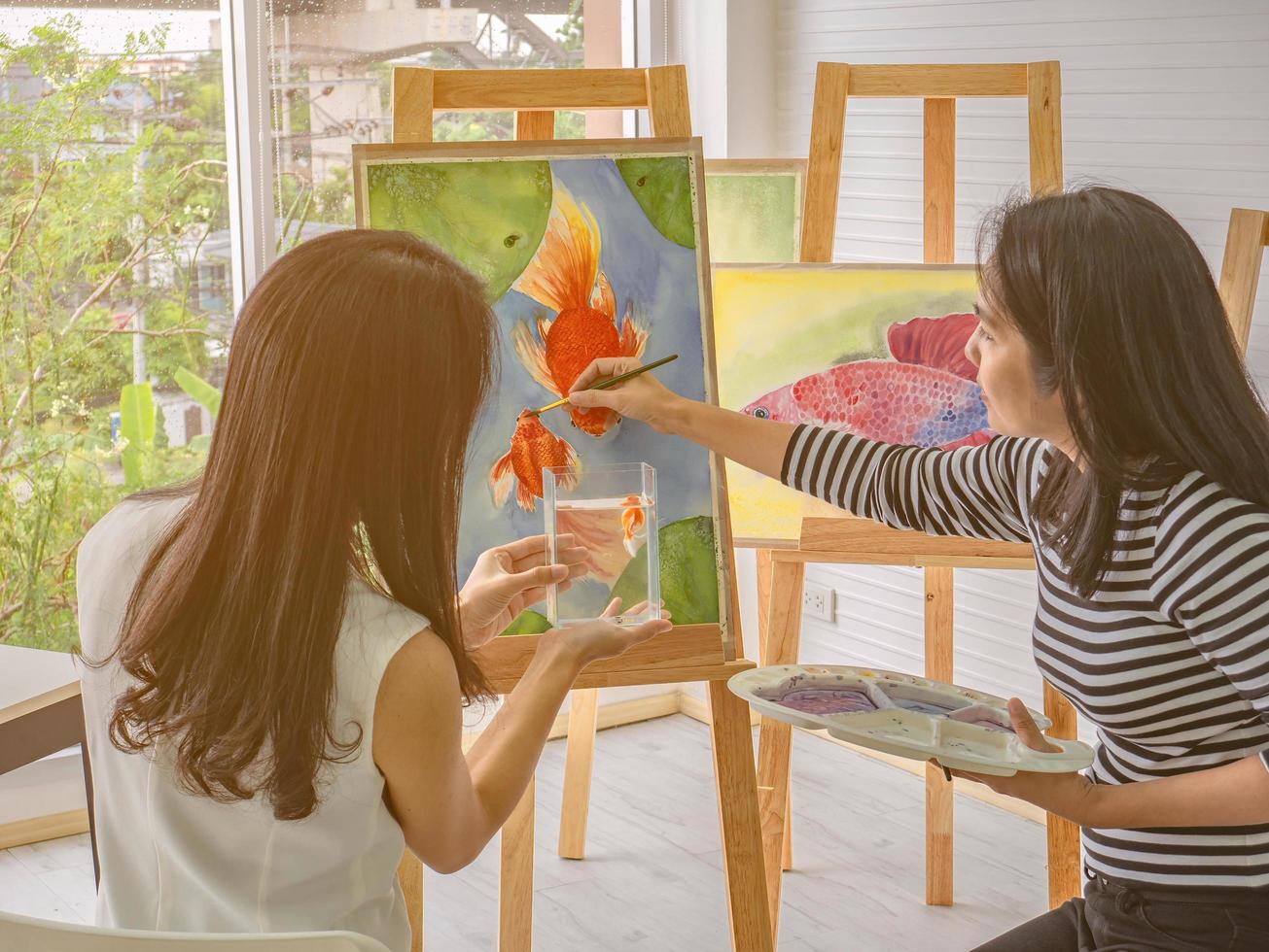 twee jong Aziatisch vrouw artiest dageraad terwijl met behulp van ideeën naar denken en creëren de het beste artwork samen, vissen concept foto