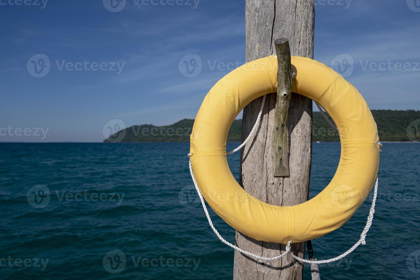 luxe klassiek veiligheid torus gedekt door geel lap. het blijft hangen Aan naar oud houten pool afrekenen Aan de steiger in de zee. foto