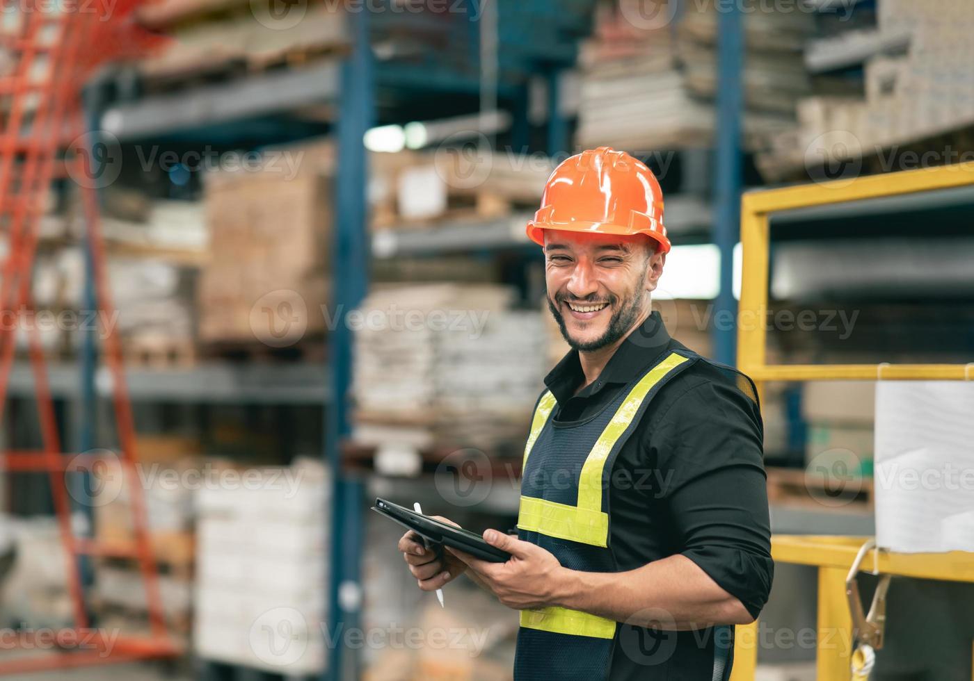 professioneel manager Mens werknemer gebruik makend van tablet controleren voorraad werken Bij magazijn. arbeider vervelend hoog zichtbaarheid kleding en een moeilijk hoed, helm en controle en tellen omhoog goederen of dozen voor levering. foto