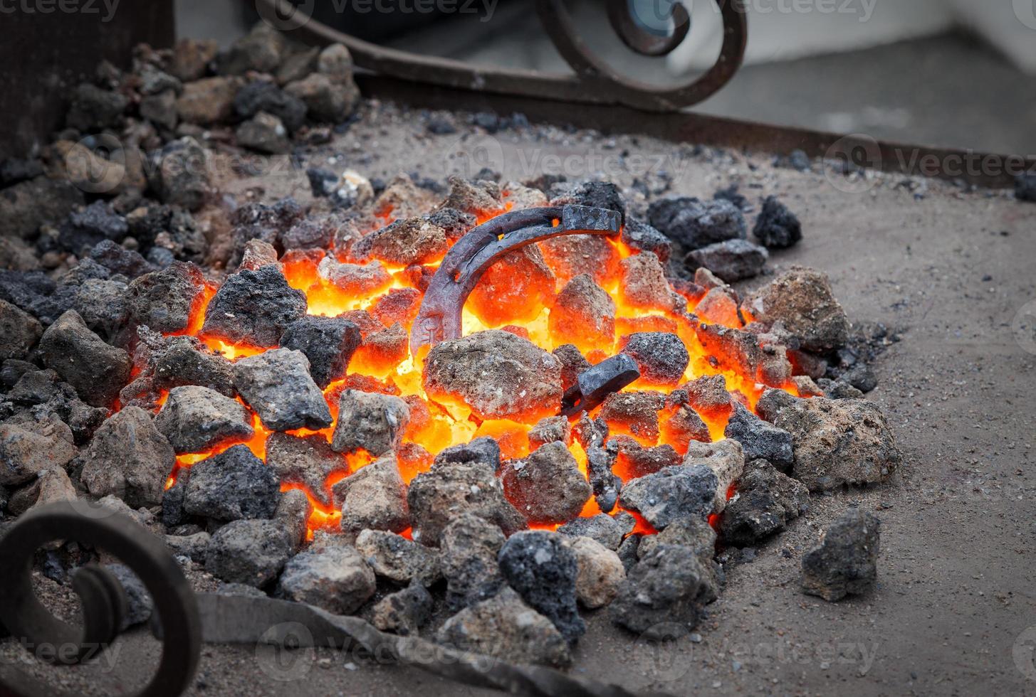 smeden, metalen hoefijzer wordt in de smidse op kolen verwarmd foto