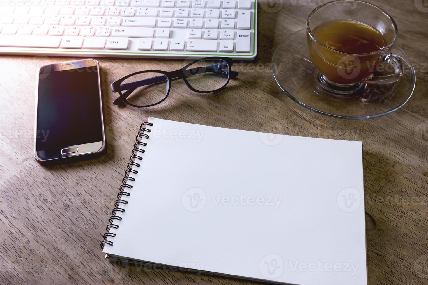 notitieboekje en smartphone en toetsenbord Aan houten bureau, zakelijk concept foto