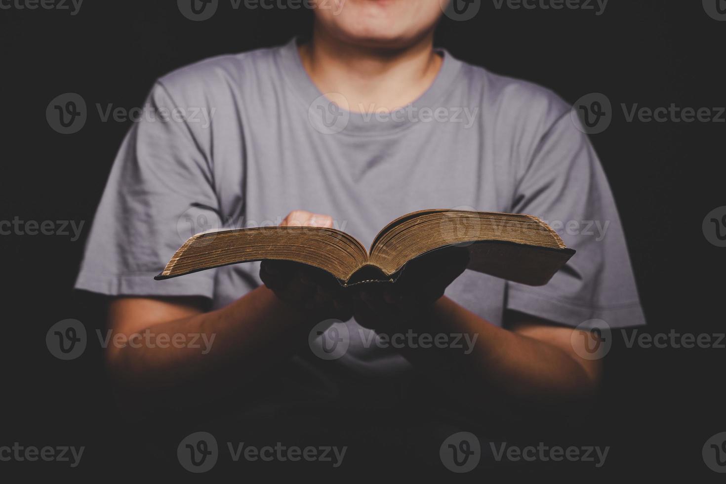 close-up van de christelijke vrouw hand met heilige bijbel bidden en aanbidden voor god zij dank in de kerk met zwarte achtergrond, volwassen vrouwelijke persoon leest boek, foto