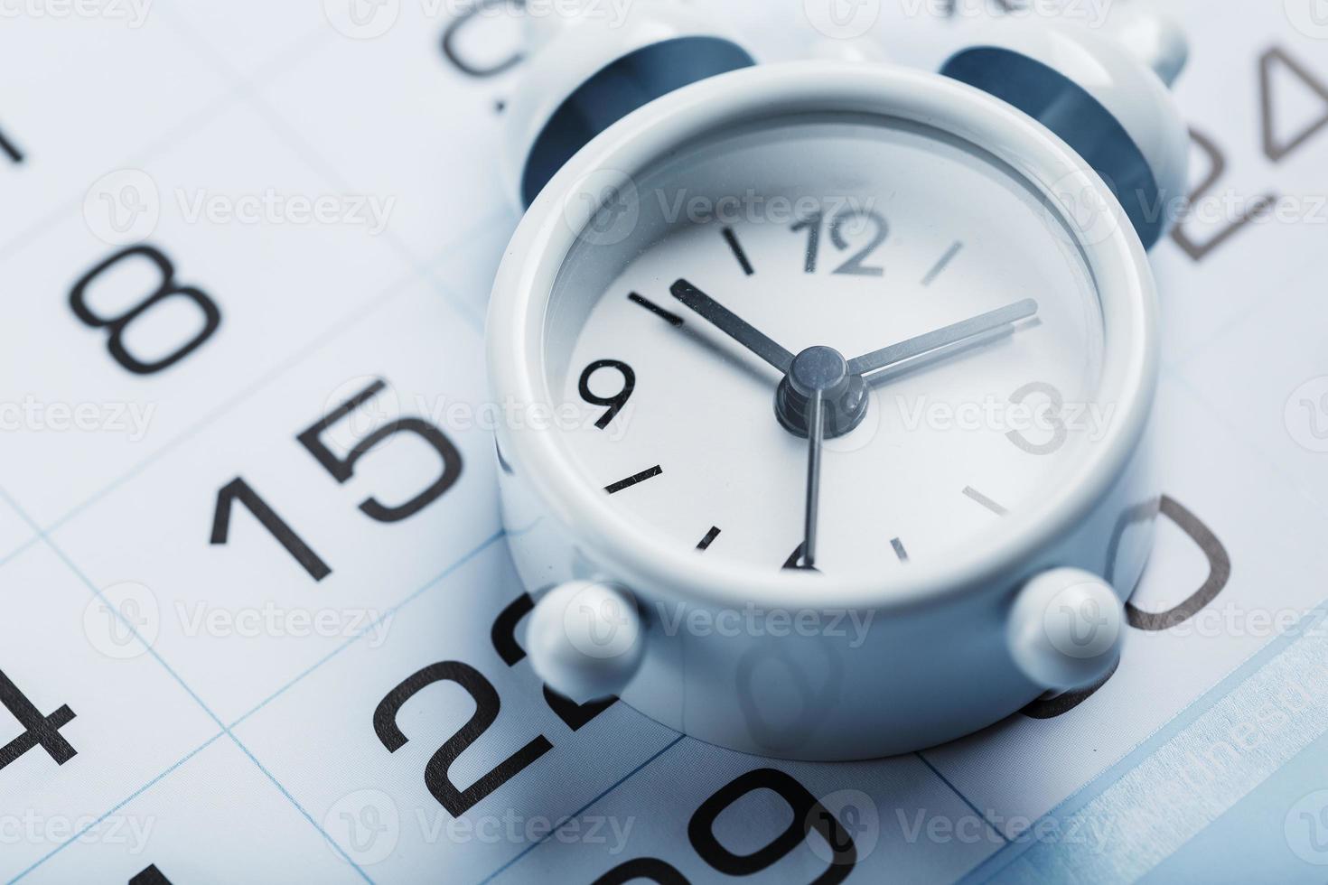 jaar- kalender met een wit alarm klok Aan een blauw achtergrond foto