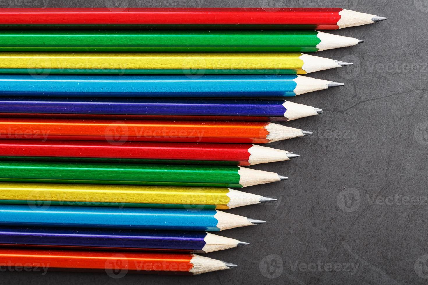 potloden van verschillend kleuren in een rij Aan een zwart getextureerde achtergrond. foto