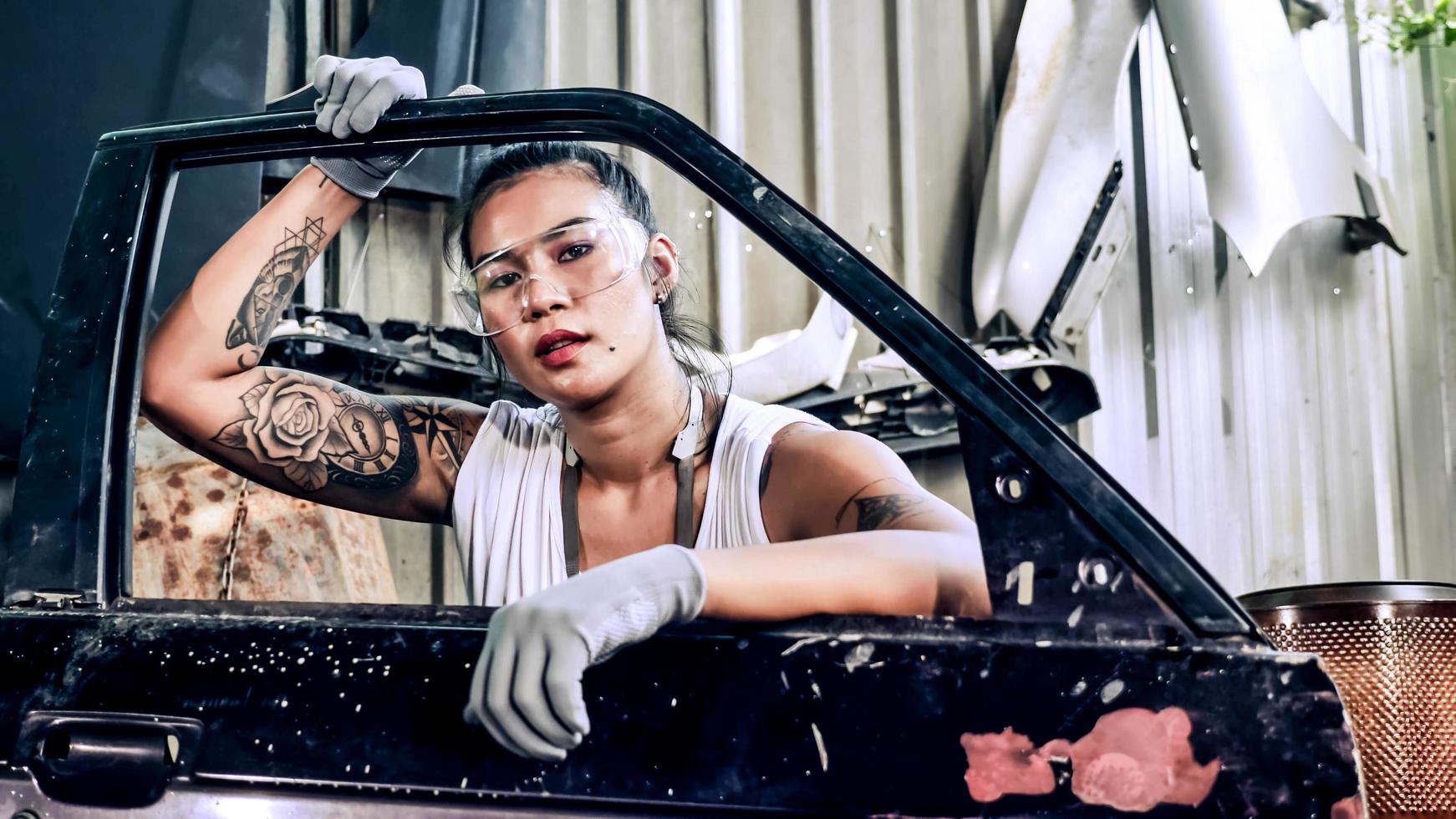 aantrekkelijk jong vrouw mechanisch arbeider repareren een wijnoogst auto in oud garage. foto