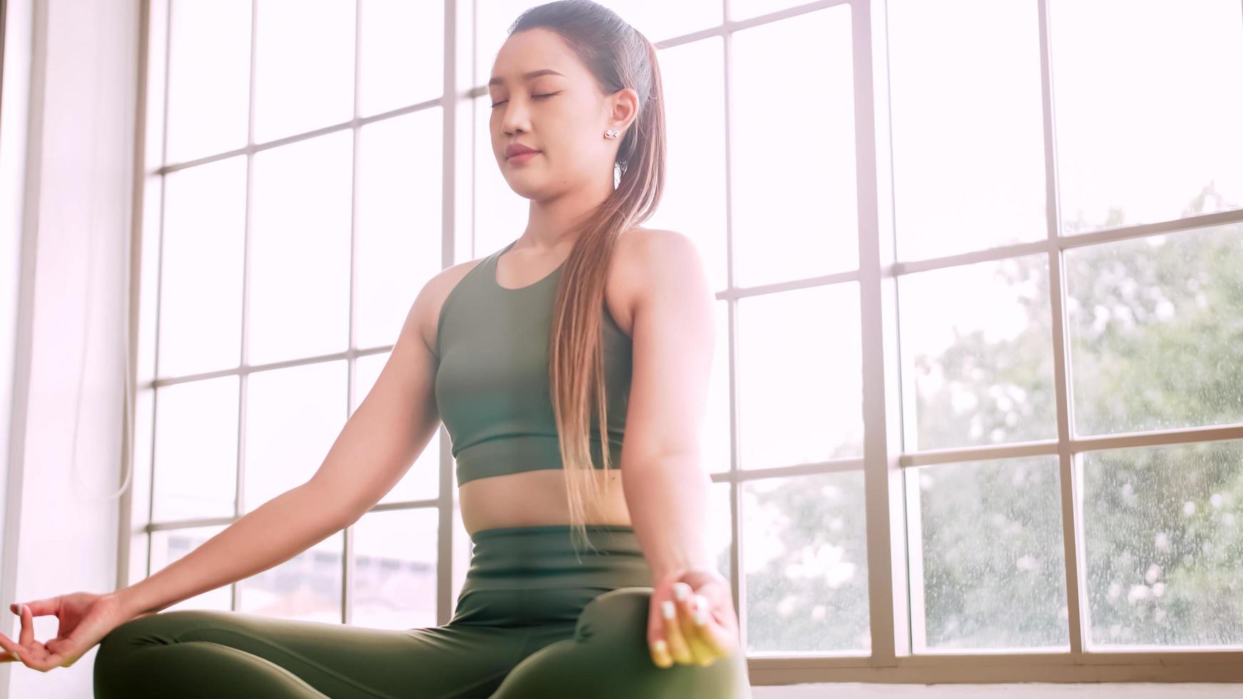 jong Aziatisch vrouw aan het doen yoga oefening Bij huis. foto