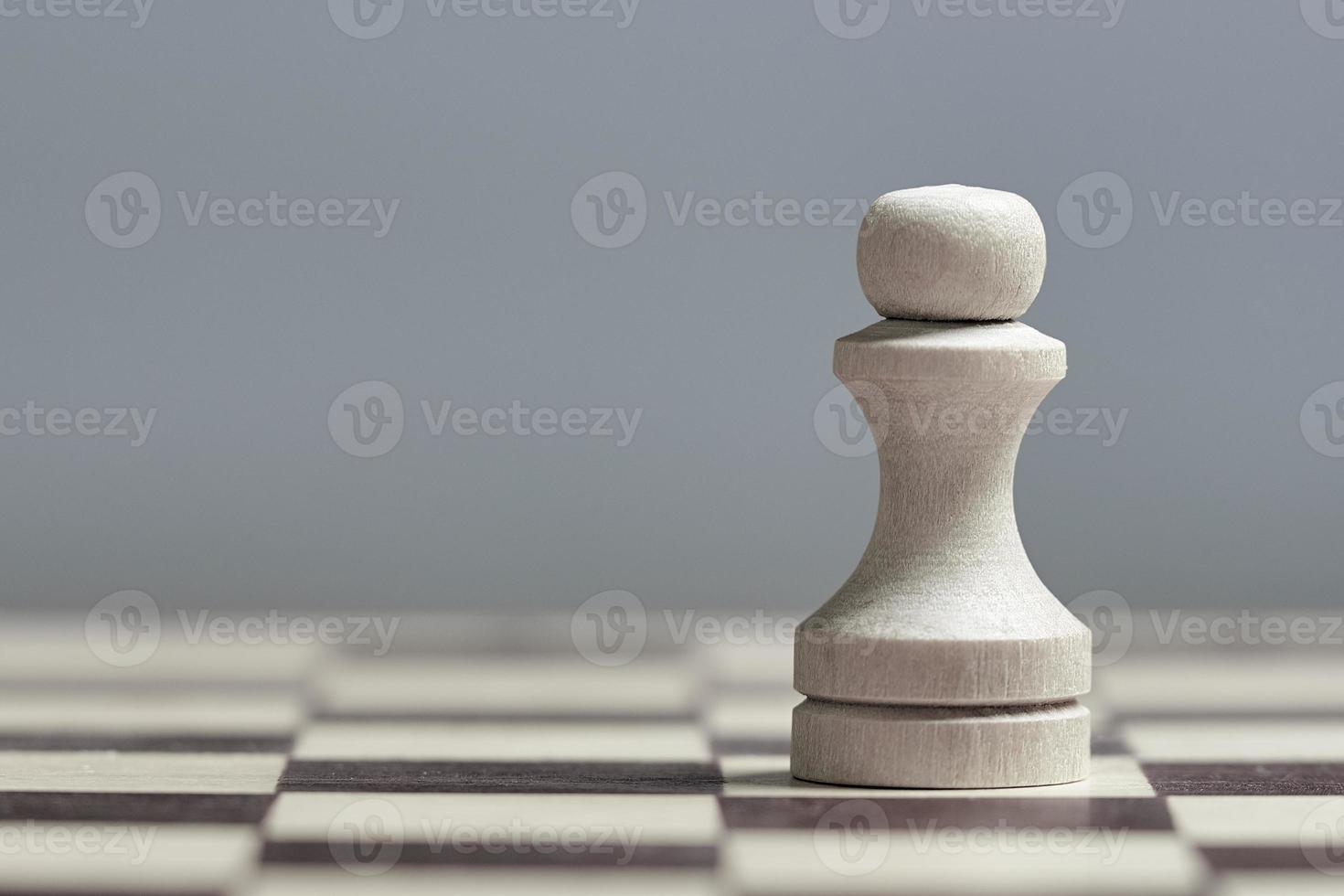een wit pion detailopname Aan een schaakbord Aan een grijs achtergrond. foto met kopiëren ruimte.