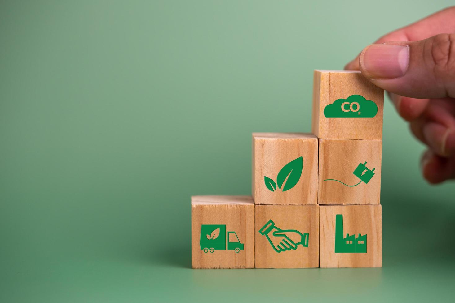 hand- Holding hout kubus blok icoon co2 koolstof credit en eco energie groen technologie Aan groen achtergrond. foto