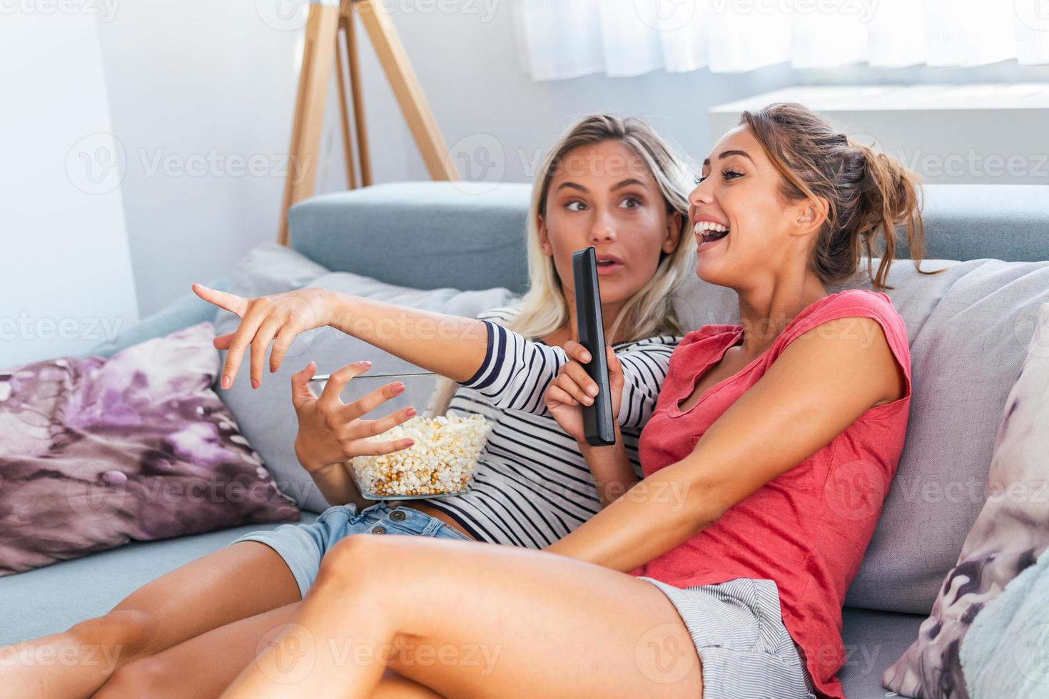 portret van grappig en gelukkig jong Dames aan het kijken komedie in bed en lachend. vrolijk vrienden aan het eten smakelijk popcorn en op zoek film met blijdschap. knus en vriendelijk atmosfeer foto